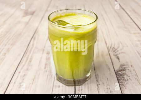 Gros plan des mains tenant un verre de thé matcha glacé aux herbes et au citron dans un café en plein air, un moment de rafraîchissement estival Banque D'Images