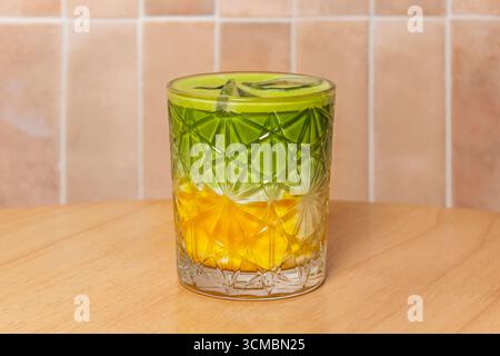 Thé matcha vert vibrant dans un verre clair sur une table en bois, mousseux et frais, une boisson japonaise traditionnelle pleine d'antioxydants et de saveur. Banque D'Images