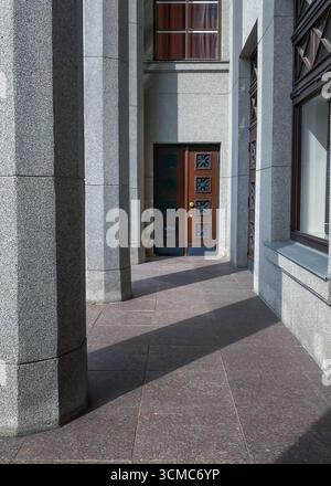 Bâtiment d'architecture géométrique avec colonnade et grande porte en bois. Arrière-plan de perspective de géométrie minimaliste. Façade murale en ciment Banque D'Images