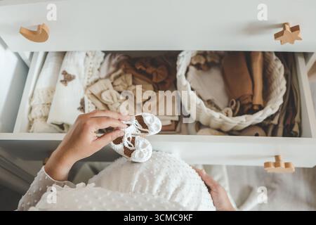 Pantoufles tricotées à la main pour enfants dans les mains. La femme enceinte se prépare pour la maternité, emballant des trucs pour bébé. preparin femme enceinte Banque D'Images