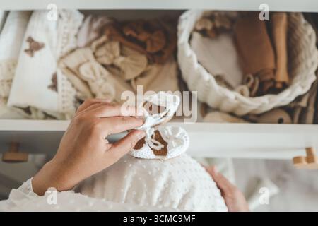 Pantoufles tricotées à la main pour enfants dans les mains. La femme enceinte se prépare pour la maternité, emballant des trucs pour bébé. preparin femme enceinte Banque D'Images