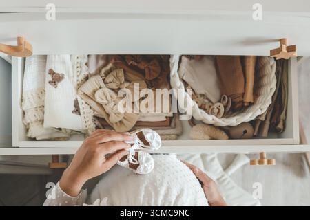 Pantoufles tricotées à la main pour enfants dans les mains. La femme enceinte se prépare pour la maternité, emballant des trucs pour bébé. preparin femme enceinte Banque D'Images