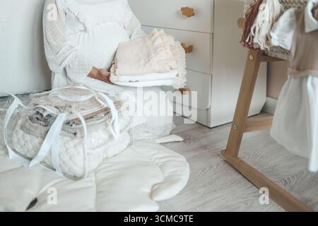 La femme enceinte se prépare pour la maternité, emballant des trucs pour bébé. femme enceinte préparant et planifiant des vêtements pour bébé. Banque D'Images