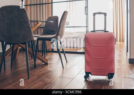 Valise rose dans une chambre d'hôtel lumineuse. Banque D'Images