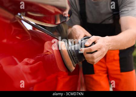 Homme polissant voiture avec polisseuse orbitale à l'extérieur, gros plan Banque D'Images