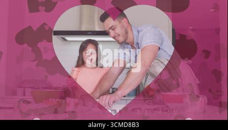 Père portant un tablier rayé et fille mélangeant la pâte dans la cuisine, avec rouleau à pâtisserie, coeur rose Banque D'Images