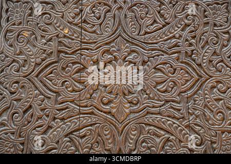 Vue rapprochée de la sculpture traditionnelle sur bois avec un design floral et géométrique sur l'ancienne porte de madrasa, Hisor ou Hissar, Tadjikistan Banque D'Images
