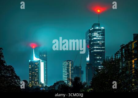 Un paysage urbain nocturne atmosphérique de Vienne, en Autriche, où les gratte-ciels modernes illuminés sont spectaculairement enveloppés de brouillard et de brume. Banque D'Images