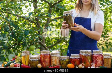 femme en conserve tomates concombres légumes sur le fond de la nature. Mise au point sélective. Banque D'Images