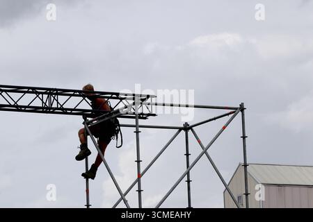 Équipage en casques et gilets abaisser les sections métalliques tout en démontant les installations après Sail 2025 à Amsterdam, pays-Bas, travail d'équipe dans une rue. Banque D'Images