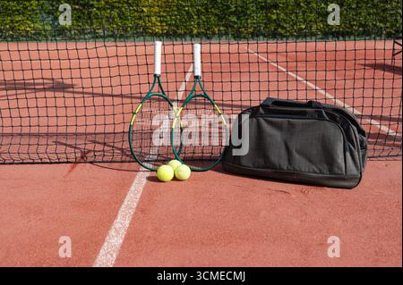 Sur un court de tennis bien entretenu, il y a deux raquettes de tennis ainsi que deux balles de tennis lumineuses, prêtes pour un match ou une séance de pratique Banque D'Images