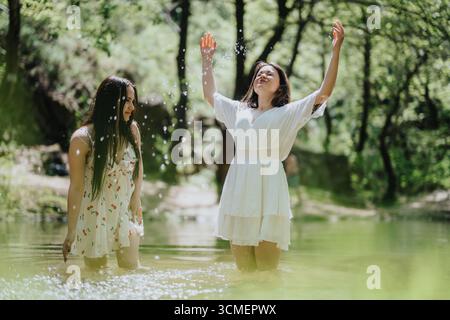 Deux femmes appréciant la nature par un ruisseau forestier ensoleillé sur une belle journée Banque D'Images