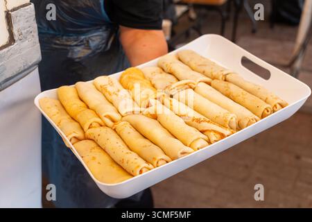 Un chef vous présente fièrement un plateau de crêpes dorées au fromage cottage fraîchement préparées, prêtes pour le petit déjeuner. Banque D'Images