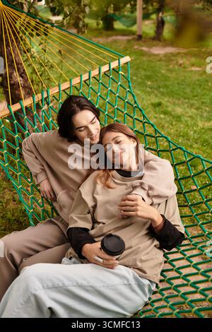 Couple aimant se détend dans un hamac vert, partageant des sourires tout en étant entouré par la beauté de la nature. Banque D'Images