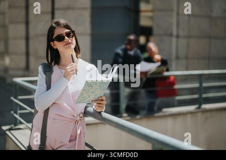 Femme professionnelle tenant un cahier et un stylo dans un cadre extérieur urbain Banque D'Images