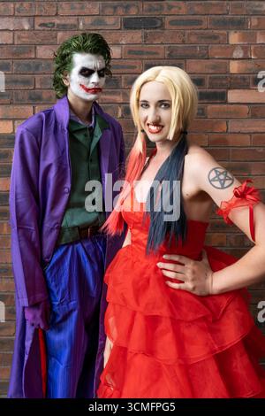 Une jolie fille et beau cosplayer masculin s'amusant et riant tout en étant habillé comme le Joker et Harley Quinn avec un espace de copie au-dessus Banque D'Images