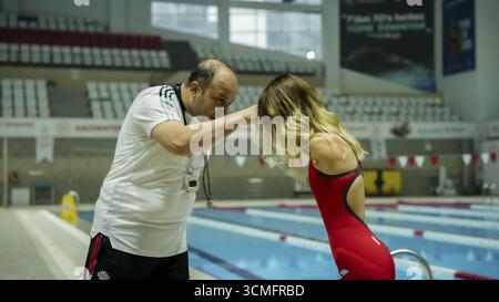 Une nageuse paralympique amputée des bras effectue des exercices d'échauffement sur une natte avant d'entrer dans la piscine pour l'entraînement, Gaziantep, Gaziant Banque D'Images