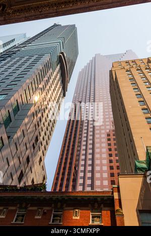 Regardant vers le haut les gratte-ciels imposants comme des géants pointant vers le ciel. Lignes de perspective fortes pointant vers le haut. Reflets du soleil dans le verre Banque D'Images