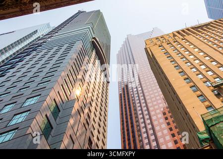 Regardant vers le haut les gratte-ciels imposants comme des géants pointant vers le ciel. Lignes de perspective fortes pointant vers le haut. Reflets du soleil dans le verre Banque D'Images