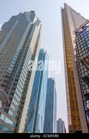 Regardant vers le haut les gratte-ciels imposants comme des géants pointant vers le ciel. Lignes de perspective fortes pointant vers le haut. Reflets du soleil dans le verre Banque D'Images