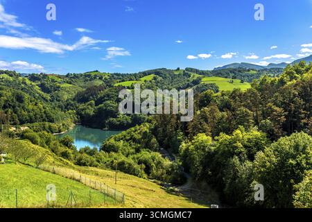 Le réservoir d'Ibiur reflète le ciel bleu vif au milieu des collines verdoyantes et des forêts luxuriantes de tolosa, gipuzkoa, au cœur du pays basque Banque D'Images