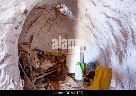 Vue intérieure grand angle d'une habitation de grotte. Le plafond haut en forme de dôme est rugueux et texturé. L'espace est rempli d'un cadre en métal, divers plastiques Banque D'Images