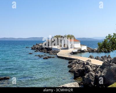Chios, petite église d'Agios Isidoros, Grèce. Chapelle d'architecture traditionnelle avec toit de tuiles rouges et clocher sur les rochers, journée d'été ensoleillée Banque D'Images