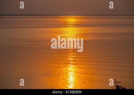Coucher de soleil doré réflexion sur les eaux calmes de la rivière Padma à Rajshahi, Bangladesh Banque D'Images