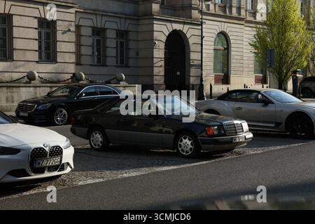 Parking de la ville de Varsovie mélange de voitures de luxe et classiques dans le soleil urbain printanier Banque D'Images