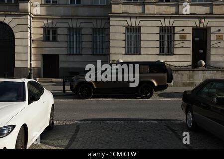 Varsovie Street avec Defender SUV, berline blanche et parking urbain automobile créatif Banque D'Images