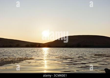 Coucher de soleil sur le réservoir Contra Loma à Antioch, Californie, qui fait partie du quartier du parc régional d'East Bay. La lumière dorée se reflète sur l'eau. Banque D'Images