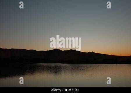 Coucher de soleil sur le réservoir Contra Loma à Antioch, Californie, qui fait partie du quartier du parc régional d'East Bay. La lumière dorée se reflète sur l'eau. Banque D'Images
