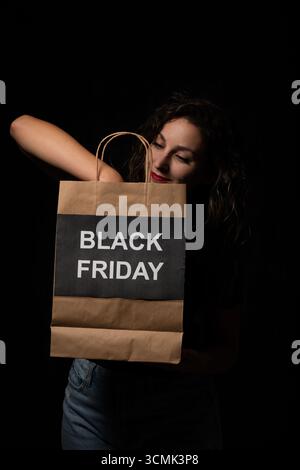 Client regardant à l'intérieur du sac à provisions avec l'écriture du vendredi noir, profitant de grandes ventes et des réductions Banque D'Images