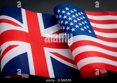 Le drapeau national du Royaume-Uni ainsi que le drapeau national des États-Unis d'Amérique isolé sur noir. Un concept de relations entre le Royaume-Uni et les États-Unis. Banque D'Images