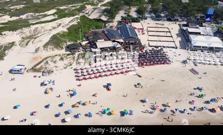 Vue aérienne panoramique de la plage de Joaquina à Florianopolis, Santa Catarina, bondé de gens et de parasols par une journée d'été ensoleillée avec bleu turquoise Banque D'Images