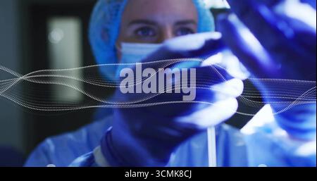 Chirurgienne pratiquant le réglage de la tubulure transparente dans la salle d'opération, avec superposition des ondes numériques Banque D'Images
