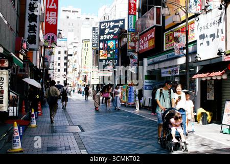 IKEBUKURO, TOKYO, JAPON - 06 septembre 2025 : des gens et une famille marchent le long d'une rue animée remplie de boutiques et de panneaux dans cette scène éditoriale franche. Banque D'Images