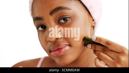 Femme noire, gua Sha et beauté en studio portrait, outils et circulation sur fond blanc. Fille africaine, bien-être et massage facial pour les soins de la peau Banque D'Images
