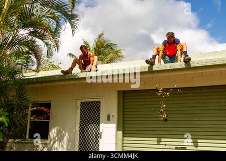 un homme au-dessus de la porte un au-dessus du toit de la porte de garage mains assises laisse tomber mains jetant quelques feuilles au-dessus des gouttières nettoyage des gouttières de toit o Banque D'Images