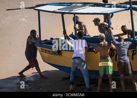 SALVADOR, BAHIA, BRÉSIL - VERS AOÛT 2025 : une équipe de pêcheurs locaux travaillent ensemble avec force et coopération pour pousser leur pêche traditionnelle b Banque D'Images