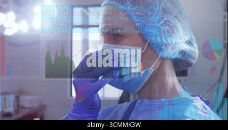 Infirmière avec gants debout portant une casquette chirurgicale, un masque et une blouse dans la chambre avec superpositions de données, espace de copie Banque D'Images