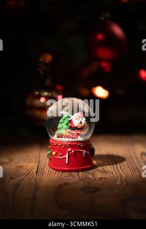 Une boule de neige vibrante présente le Père Noël et un sapin de Noël, entourés de lumières scintillantes. Posé sur une surface en bois, il capte l’esprit festif pendant la période des fêtes. Banque D'Images