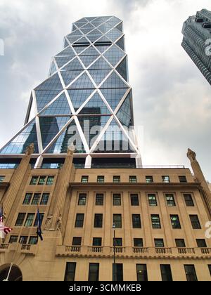 Hearst Tower à New York - Une vue en bas angle de la Hearst Tower moderne en verre à facettes s'élevant au-dessus de sa base historique classique par une journée nuageuse Banque D'Images