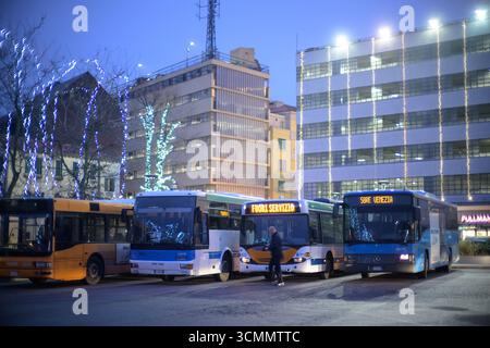 Scène matinale à Piazzale Roma à Venise, avec bus alignés et lumières de Noël brillantes créant une atmosphère festive. Banque D'Images