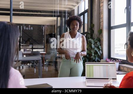 Diverses collègues féminines présentant une feuille de calcul sur ordinateur portable dans la salle de conférence Banque D'Images
