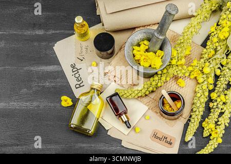 Concept de soin naturel avec fleurs Verbascum, ingrédient à base de plantes pour huiles, crèmes et soins de beauté. Fond en bois noir, vue de dessus Banque D'Images