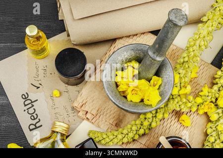 Concept de soin naturel avec fleurs Verbascum, ingrédient à base de plantes pour huiles, crèmes et soins de beauté. Fond en bois noir, vue de dessus Banque D'Images