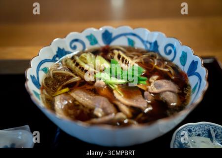 Un bol vapeur de ramen de canard japonais avec un riche bouillon, de tendres tranches de canard, des nouilles et des garnitures fraîches servies dans un style traditionnel. Banque D'Images
