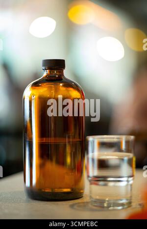 Bouteille en verre ambré avec bouchon placé sur la table dans un café, design minimaliste moderne, concept de style de vie, scène de fond bokeh floue Banque D'Images