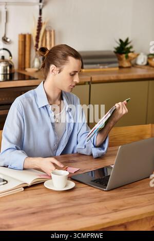 Un jeune homme avec une touche féminine s'engage activement avec des notes colorées et un magazine tout en travaillant. Banque D'Images